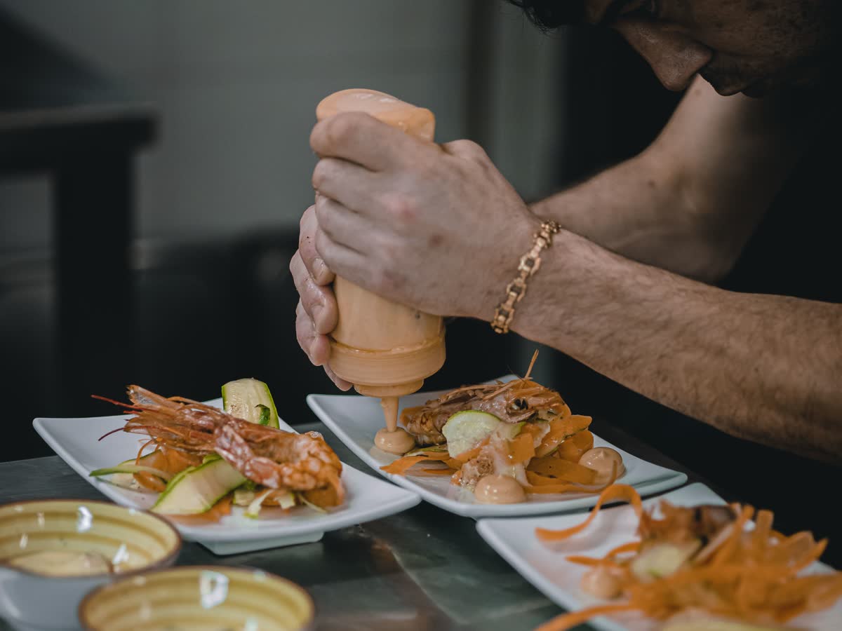 Un cuisinier termine le dressage de plusieurs assiettes
